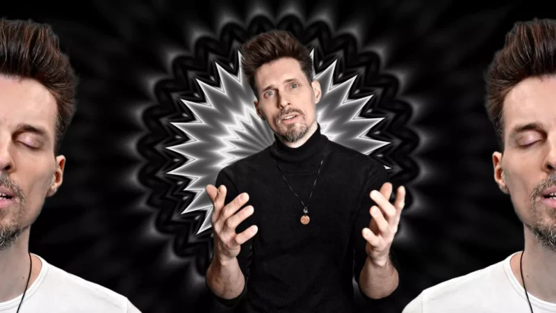 Muž v čiernom roláku so zdvihnutými rukami stojí pred čiernobielym radiálnym vzorom. Na oboch stranách sa objavujú dva čiastočné profily jeho tváre. Mystický tón.