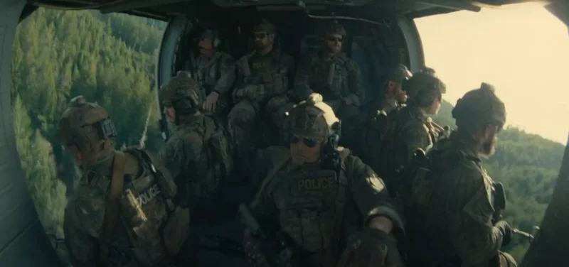 Osem ozbrojených vojakov v taktickej výstroji sedí vo vrtuľníku a prelieta nad zalesnenou oblasťou. Nálada je napätá a sústredená, na ich vestách je viditeľný nápis „Polícia“.