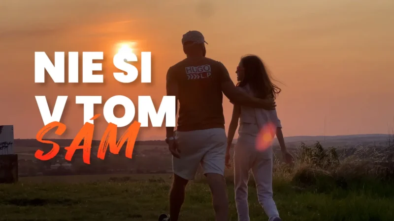 Pár sa kráča ruka v ruke pri západe slnka po trávnatom kopci a vyjadruje tak teplo a priateľstvo. Cez obrázok je napísaný slovenský text „NIE SI V TOM SÁM“.
