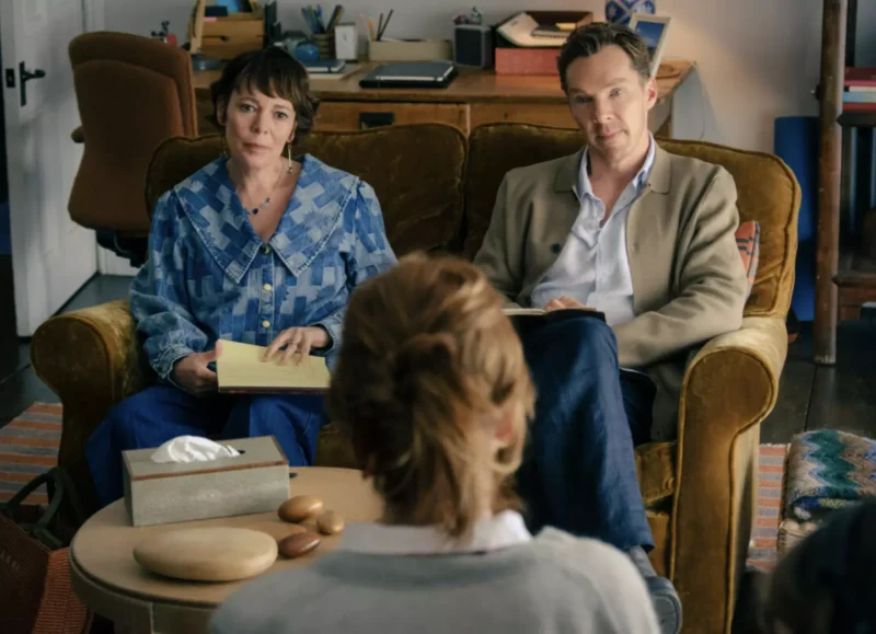 Obrázok zachytáva troch ľudí v útulnej miestnosti: dvaja sedia na žltom gauči, píšu si poznámky do zápisníka, jeden sedí oproti nim pri stole. Na stole sú dekoratívne kamene a krabica na servítky. V pozadí je pracovný stôl so zápisníkmi, perami a ďalšími osobnými predmetmi, čo pripomína atmosféru porady alebo konzultácie. Celkové prostredie pôsobí domácky, uvoľnene a dôverne.