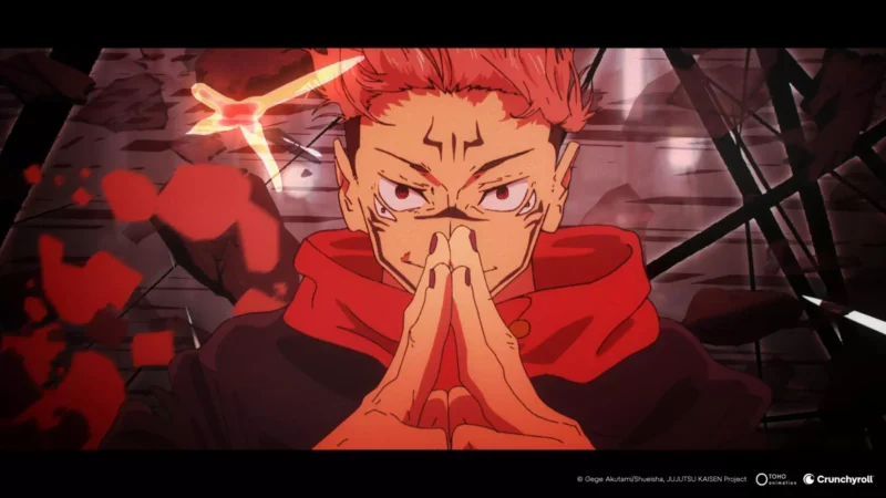Anime postava s ryšavými vlasmi na špicatých orieškoch sa sústredí s rukami v geste, obklopená víriacou červenou energiou a intenzívnym výrazom, zasadená do tmavého, rozbitého pozadia.