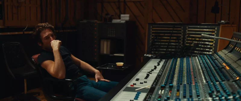 Muž v nahrávacom štúdiu zamyslene sedí na stoličke s bradou opretou o ruku. Veľký mixážny pult vypĺňa popredie a vyvoláva sústredenie a introspekciu.