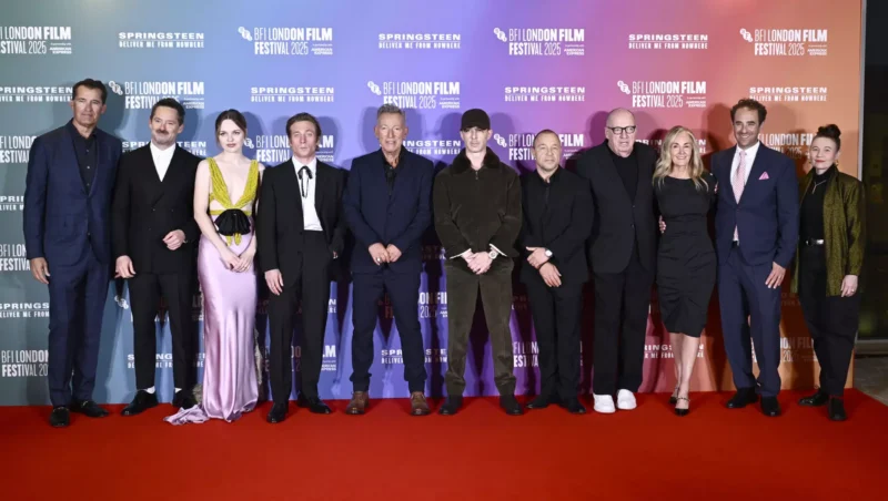 Skupina jedenástich ľudí oblečených vo formálnom oblečení stojí na červenom koberci na filmovom festivale BFI London 2023. Na pozadí sú zobrazené logá festivalu.