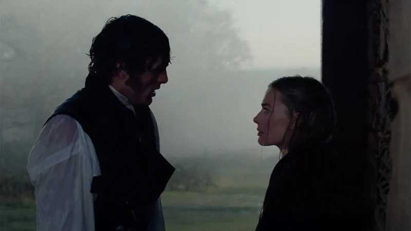 Muž a žena stoja oproti sebe v slabo osvetlenom, hmlistom vonkajšom prostredí. Ich výrazy sú vážne, čo naznačuje hlboký rozhovor alebo emocionálny okamih.