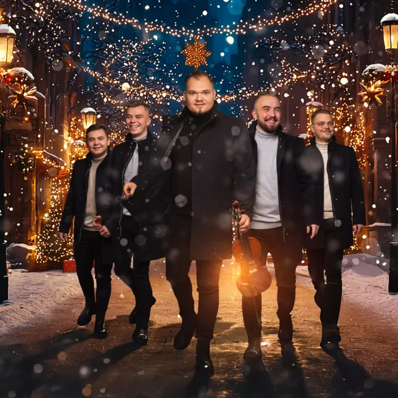 Päť mužov v zimných kabátoch veselo kráčajú po zasneženej, osvetlenej ulici ozdobenej slávnostnými svetlami a veľkou hviezdou nad hlavou. Jeden drží husle.