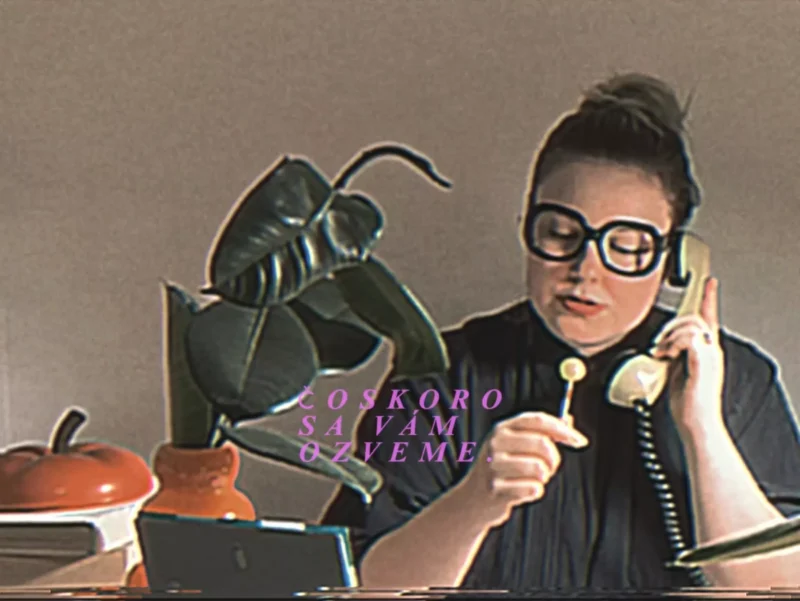 Muž s veľkými okuliarmi, držiaci telefón a lízatko, sedí pri rastline a knihách. Na vrchu knihy je nápis v slovenčine: „Čoskoro sa vám ozveme.“ Tón je retro.