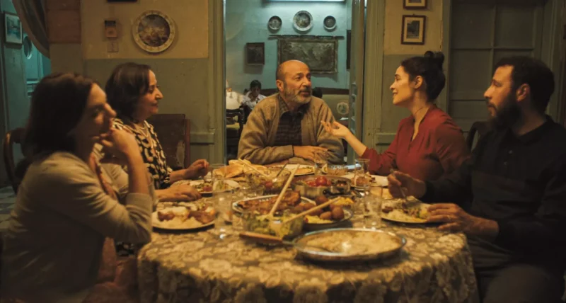 Päťčlenná rodina sa zhromažďuje okolo jedálenského stola a spoločne jejú. Živo sa rozprávajú, čím vytvárajú príjemnú a útulnú atmosféru.