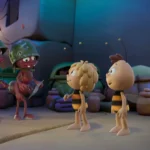 Dva animované mravce v prilbách sa rozprávajú s dvoma včelami v farebnom, rozmarnom prostredí, obklopené veľkými listami a debnami s ovocím.