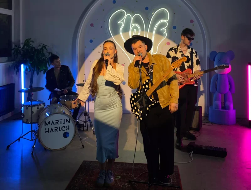 Kapela energicky vystupuje pod neónovým nápisom „láska“. Žena vo svetlomodrých šatách a muž s gitarou a klobúkom vášnivo spievajú. Bubeník a gitarista hrajú obklopení farebnými svetlami. Naboku stojí veľká socha v tvare plyšového medvedíka, ktorá dodáva scéne hravý prvok.