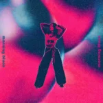 Osoba stojí na žiarivom, abstraktnom pozadí víriacej červenej a modrej. Text „Morning blues“ sa zobrazuje vertikálne na oboch stranách a vytvára zasnený tón.