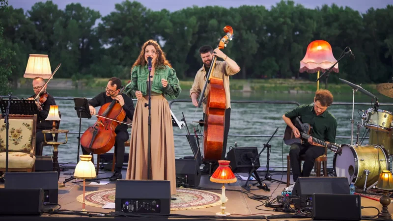 Za súmraku na pódiu pri rieke vystupuje kvinteto so speváčkou, violončelom, kontrabasom, gitarou a bicími. Scénu dotvárajú útulné lampy a pokojná atmosféra.