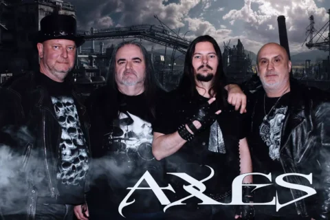 Štyria muži v čiernom rockovom oblečení pózujú pred priemyselnou panorámou zahalenou do dymu; táto atmosférická fotografia metalovej kapely nesie v spodnej časti logo „AXLES“.