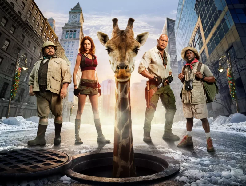 Zo šachty uprostred zasneženej mestskej ulice sa vynára žirafa, obklopená štyrmi drsnými dobrodruhmi; táto surreálna scéna pôsobí humorne a filmovo.